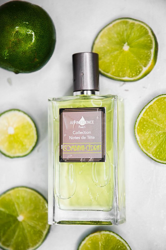 about-img Top view of a perfume bottle surrounded by fresh limes on a white background.