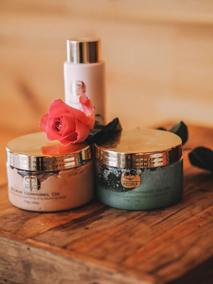 our-story Luxurious cosmetic jars with a pink rose on a rustic wooden table, perfect for beauty and skincare themes.