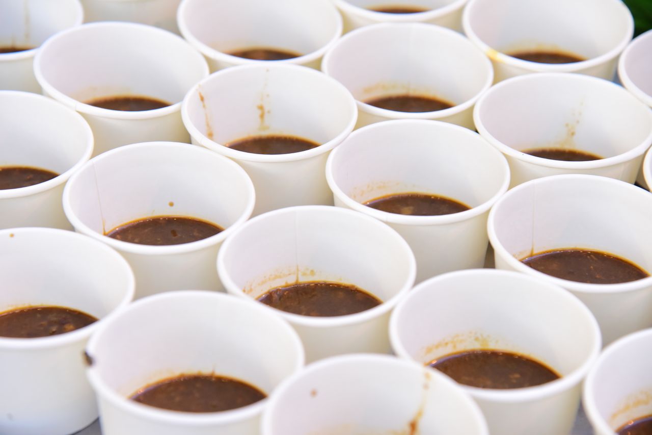 services-img Close-up of multiple white paper cups containing brown liquid, arranged uniformly.