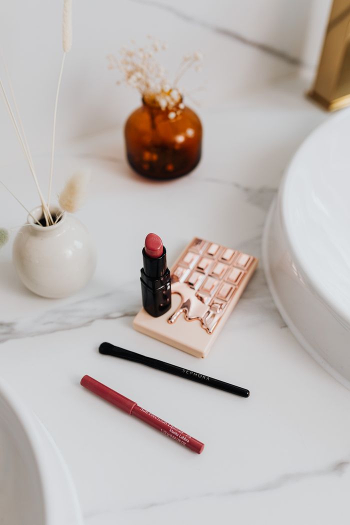 Stylish display of makeup items on marble surface with ceramic vase, ideal for beauty product promotions.